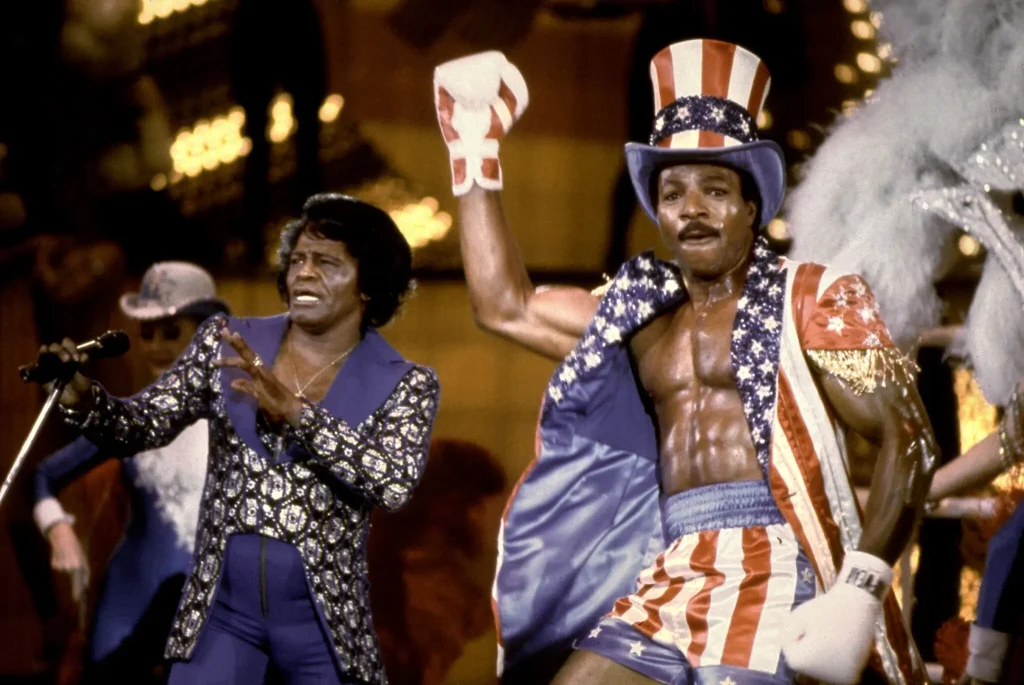 Mr. Weathers’s star-spangled entrance to a fateful fight in “Rocky IV” was accompanied by James Brown, left, singing “Living in America.”Credit...MGM, via Everett Collection